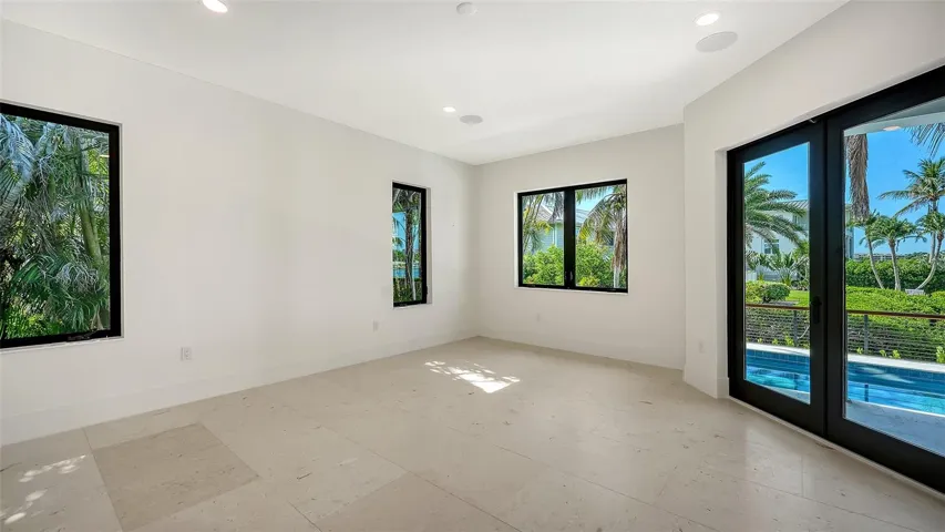 The primary suite is a peaceful sanctuary, where expansive windows, lush tropical views, and private access to the resort-style pool terrace create the perfect waterfront retreat.