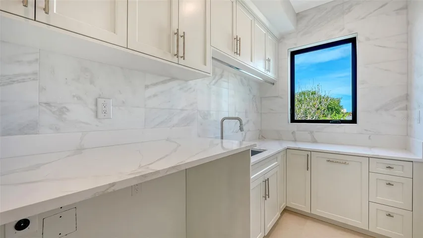 Even the laundry room reflects the home’s exceptional attention to detail, featuring custom cabinetry, abundant storage, elegant marble surfaces, and a utility sink.