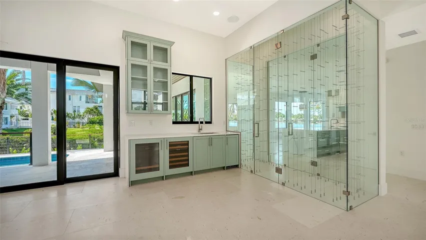 The glass-enclosed, wine room accommodates up to 160 bottles and serves as a stunning architectural showpiece, preserving uninterrupted views to the shimmering waterfront beyond while elevating the home’s sophisticated design.