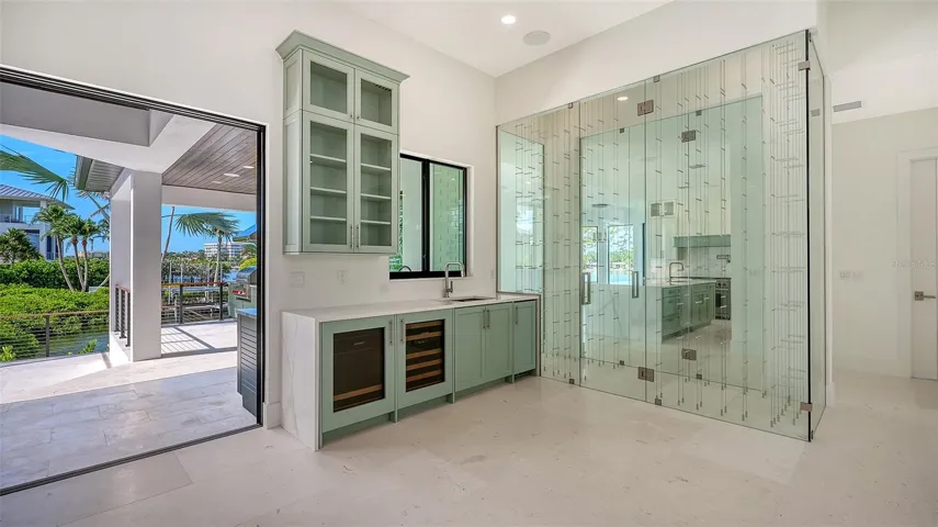 Elegant beverage center featuring custom cabinetry, dual under-counter refrigerators, and direct access to the covered lanai.
