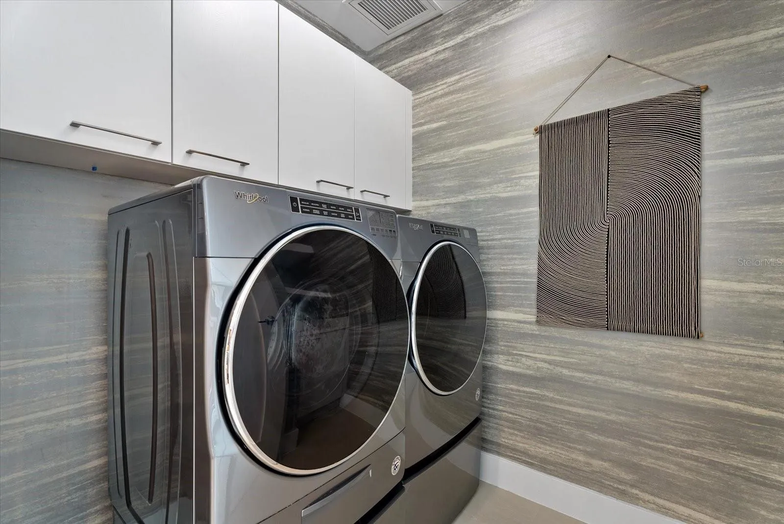 Practical storage cabinets in laundry room, across from kitchen.