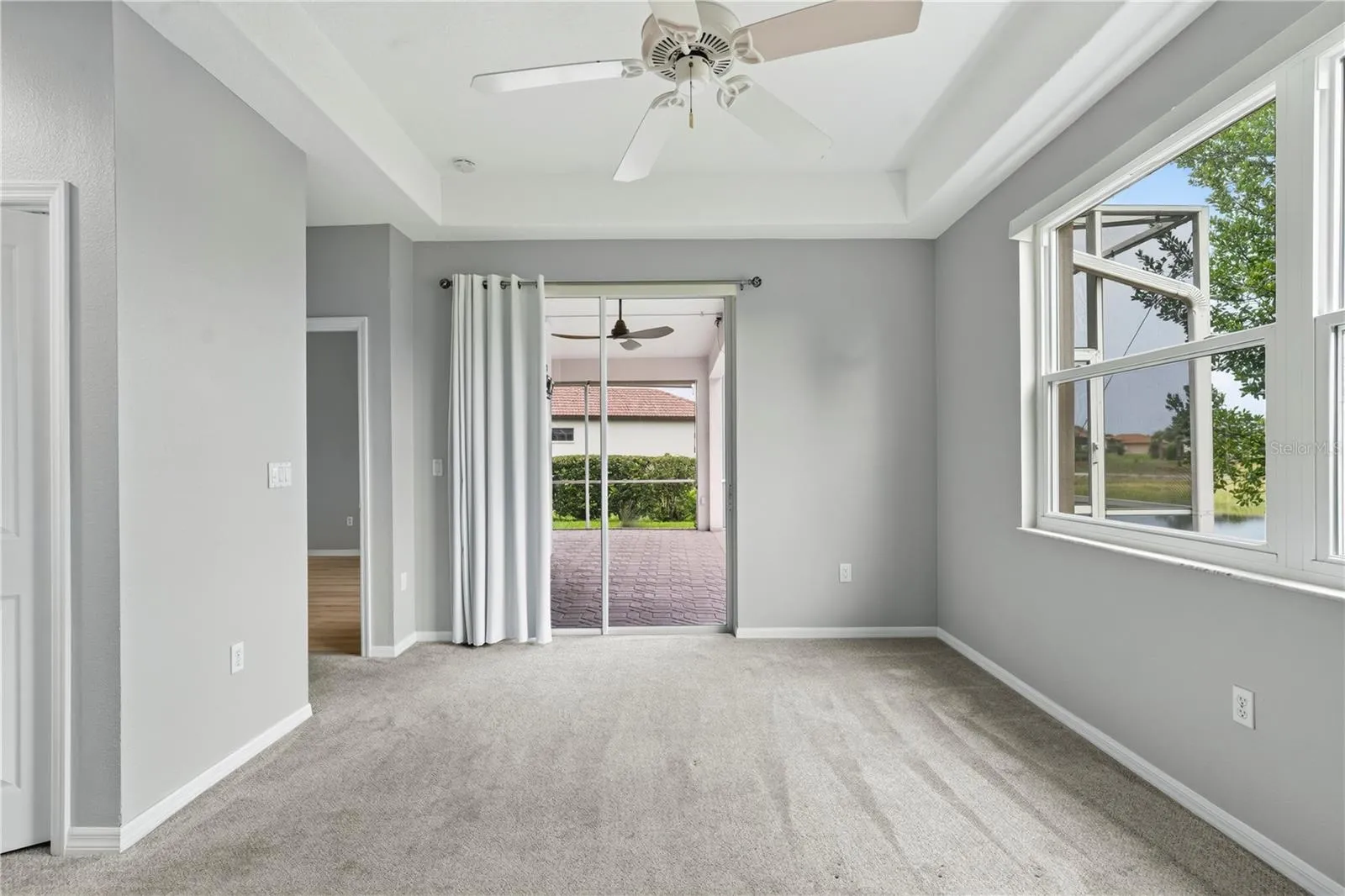 Primary bedroom w/ glass sliding doors to outside enclosed screened patio/lanai