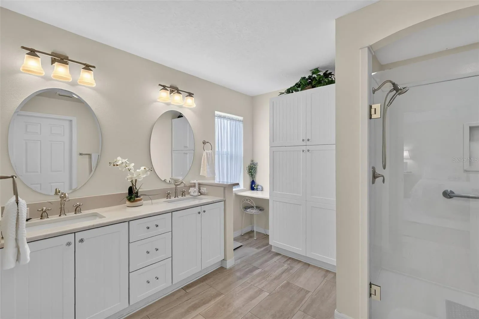 Double sink vanity with linen closet and walk in shower