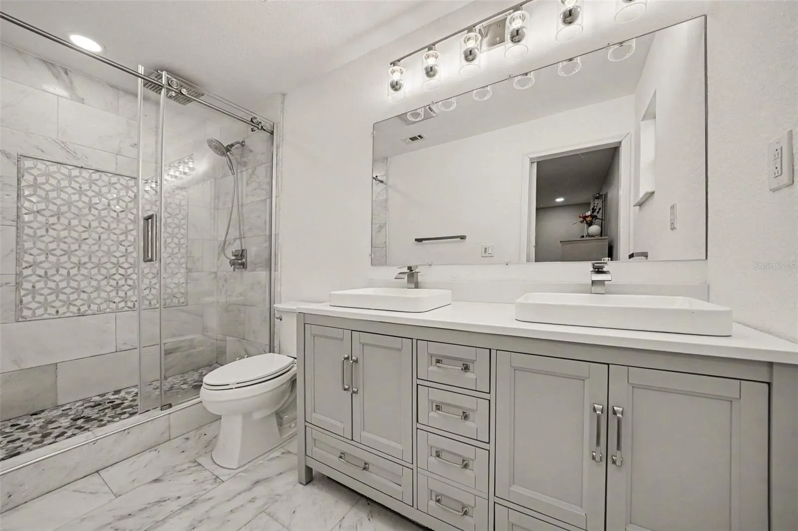 Primary Bath w/Marble tiled walk-in shower, marble tiled flooring and vanity w/ double sinks