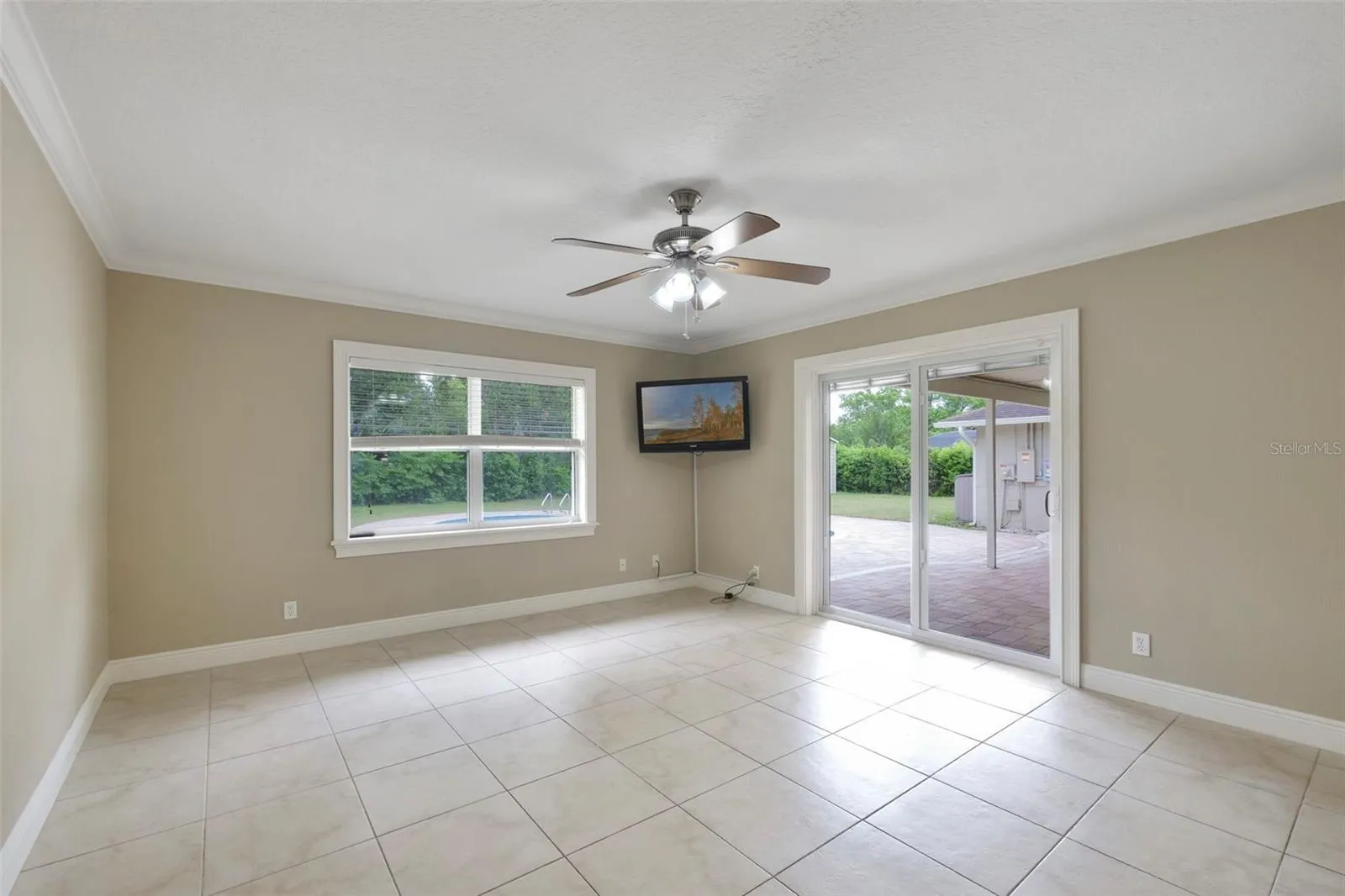 A VERSATILE BONUS SPACE is ideal as a media room, game room, or second living area, with sliding glass doors opening to the patio and pool for seamless indoor-outdoor entertaining.