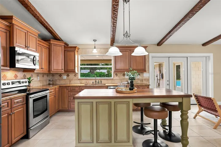 Rich wood cabinetry, abundant counter space, a center island, SLEEK TILE BACKSPLASH, stainless steel appliances, a closet pantry, and a spacious Breakfast Nook provide everything the home chef needs.