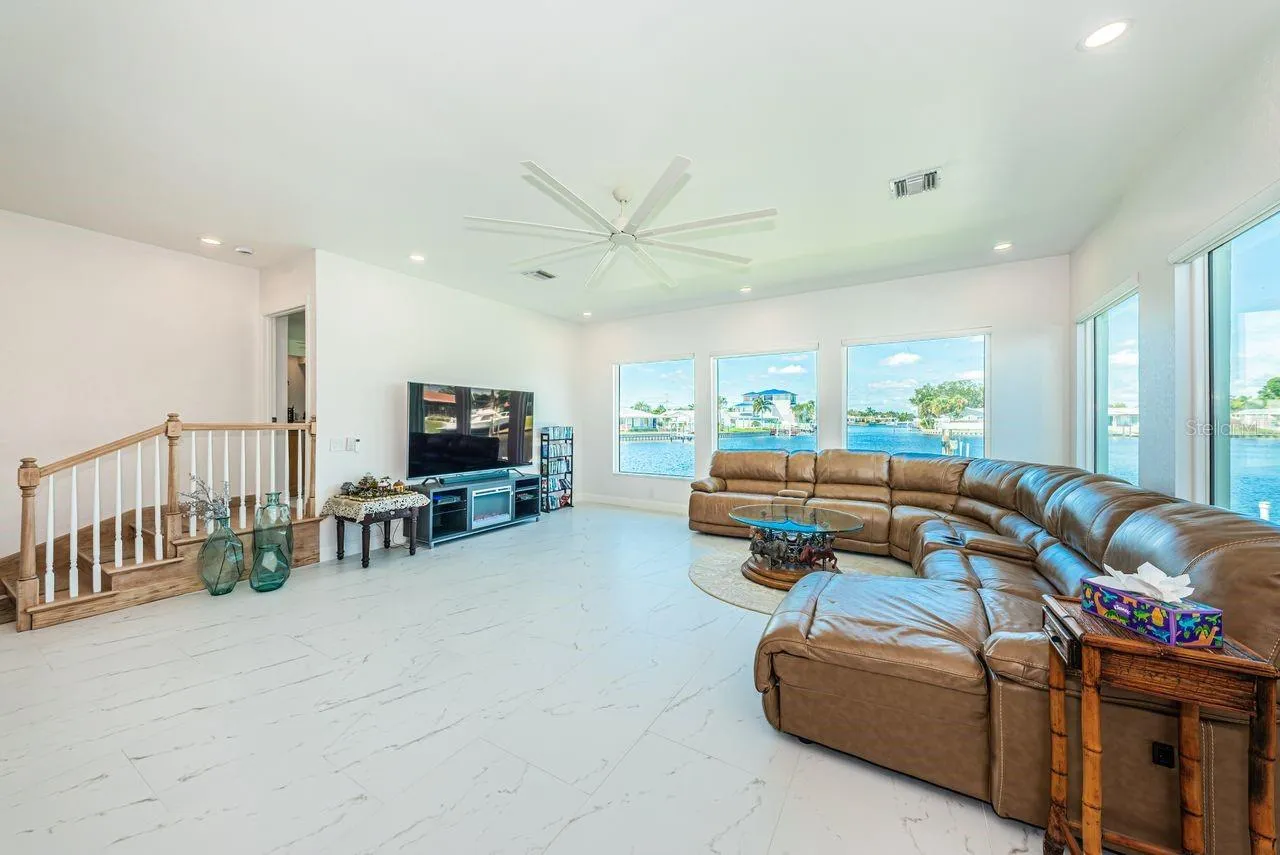 Five big picture windows allow you to enjoy the water view. 3 small steps lead to primary bedroom.