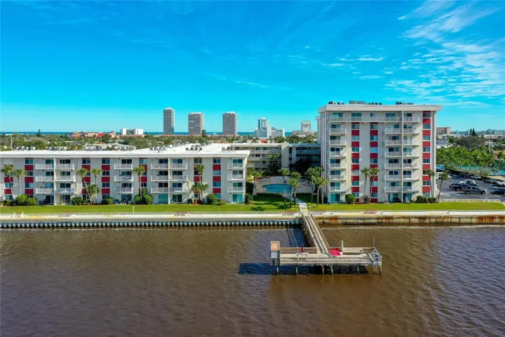 Intracoastal-side condo complex featuring vibrant architectural accents, well-kept green space, and a private dock perfect for relaxing outdoors or enjoying views of the waterway.