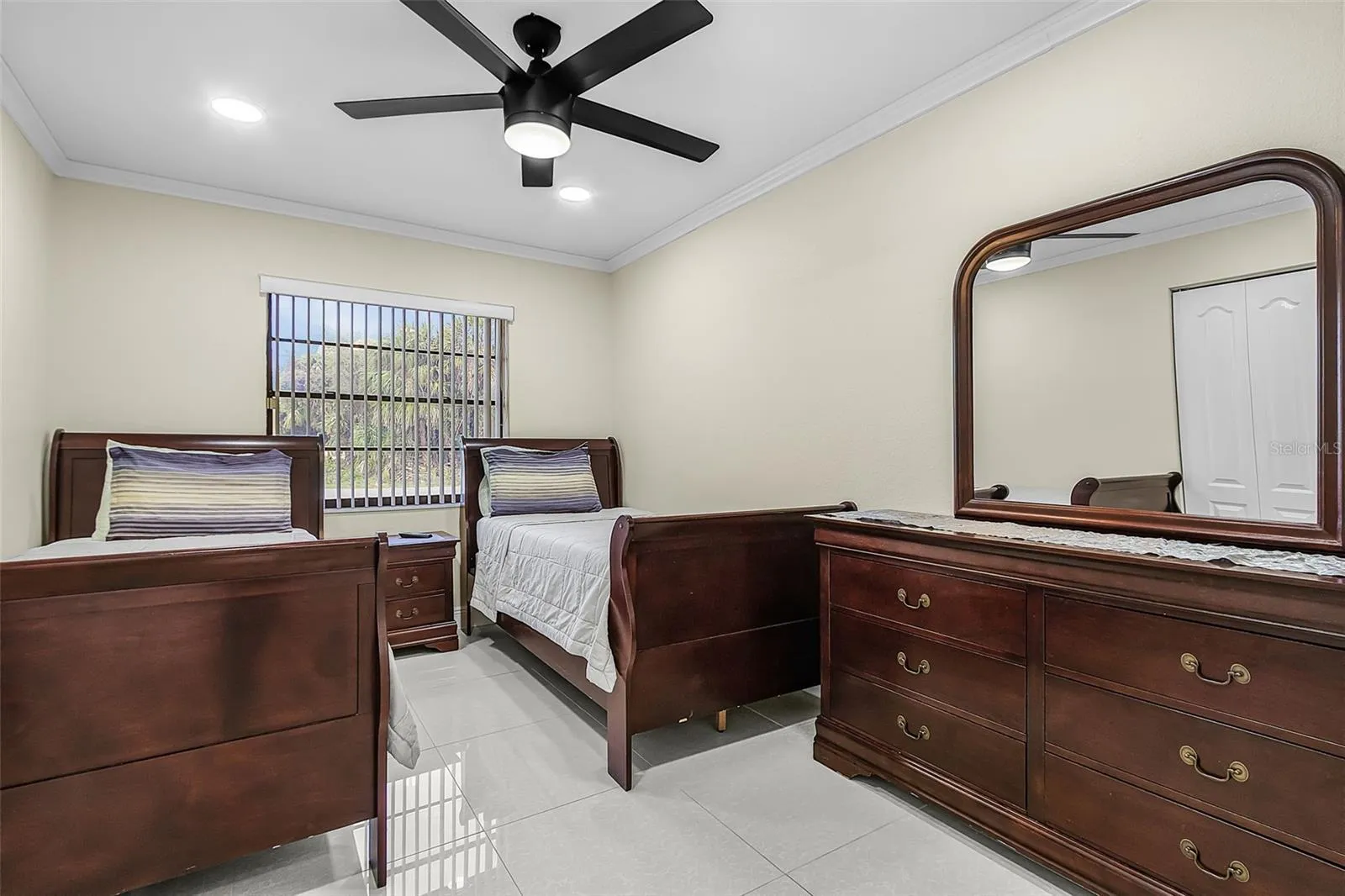 Guest bedroom with twin beds, ceiling fan, and tile flooring.