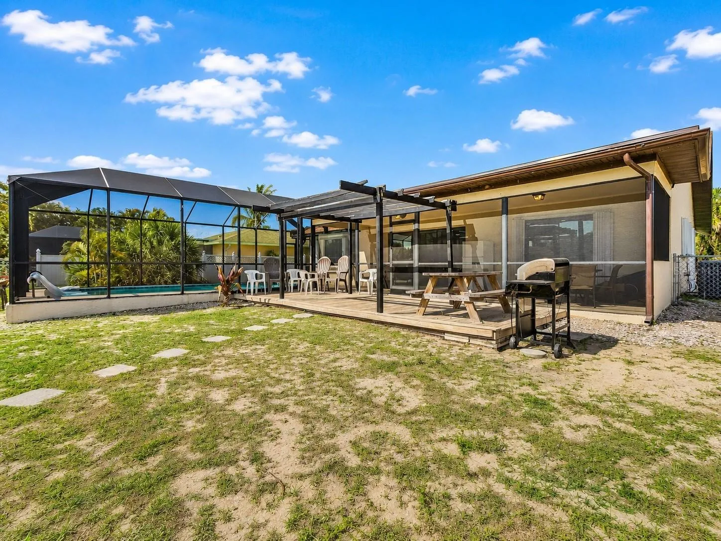 Rear exterior with screened pool enclosure, outdoor deck, and backyard entertaining space.