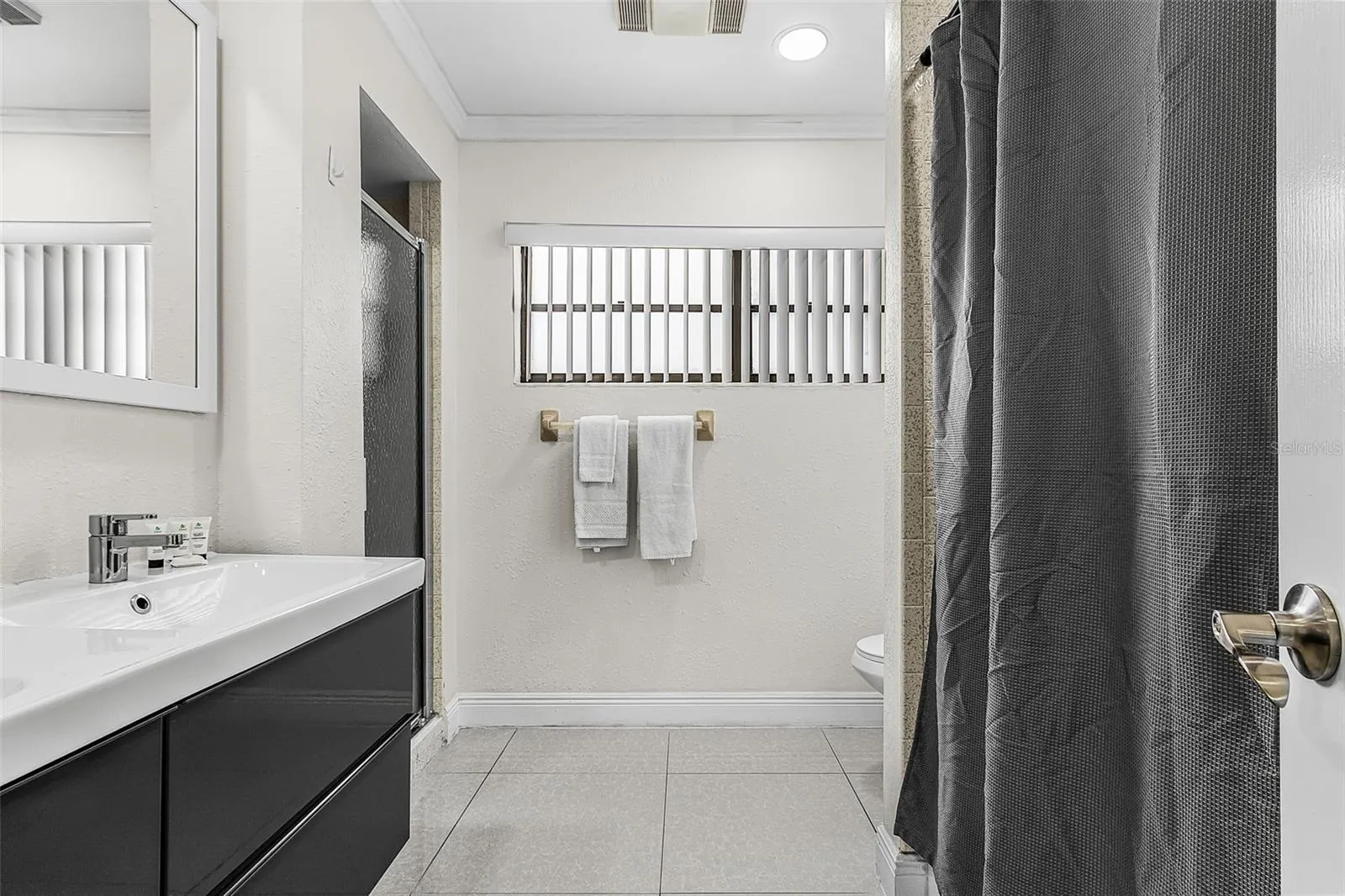 Alternative view of Full guest bathroom with modern vanity, shower and bathtub.