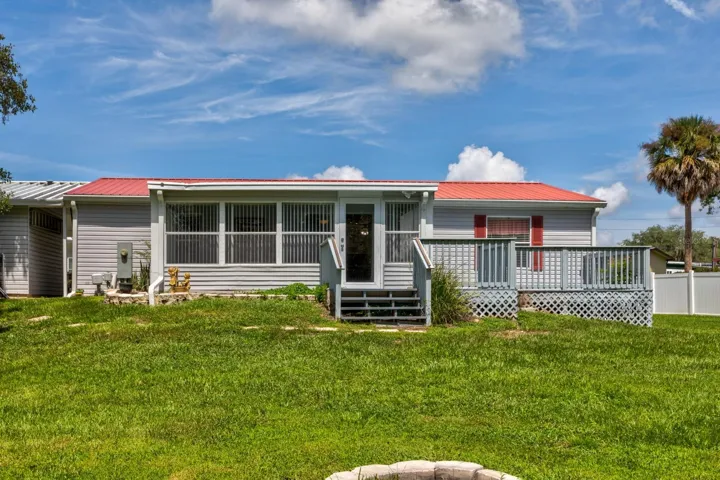 Front of home with large side deck and an entrance into glass lanai