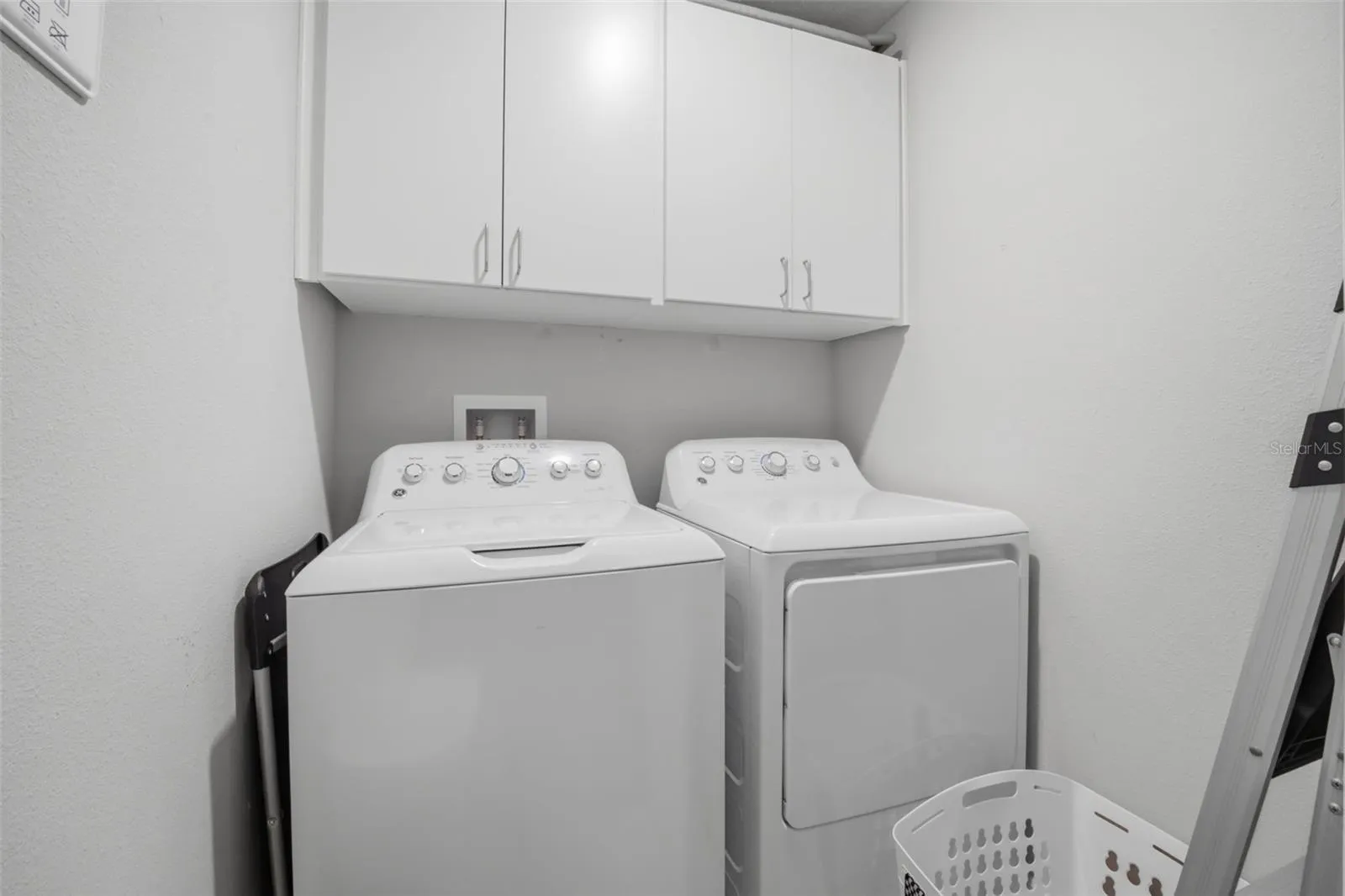 Washer and dryer with cabinets above in laundry room