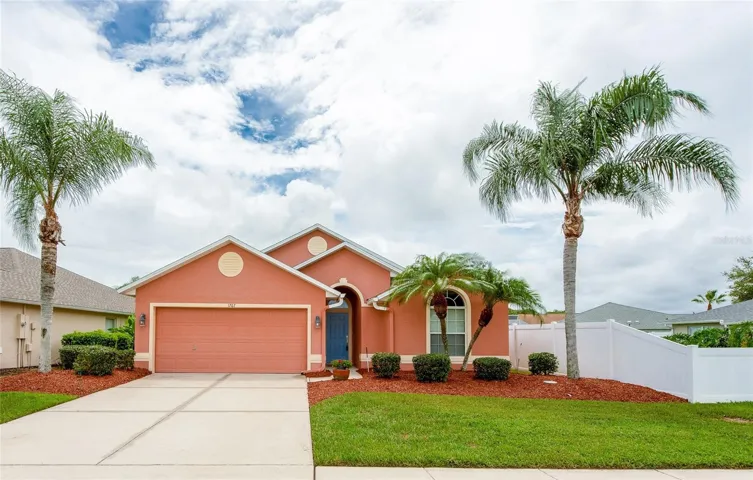 Attractive single-story home with tropical landscaping, a two-car garage, and a welcoming covered entry that creates excellent curb appeal.