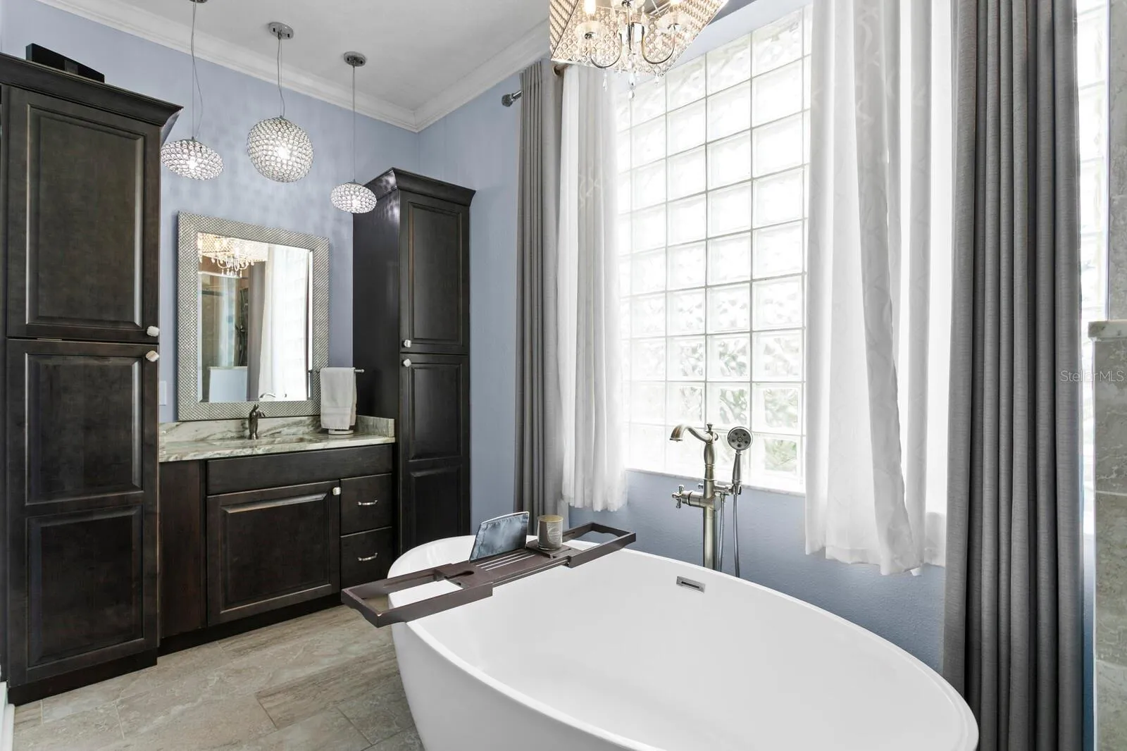Ensuite bath features custom lighting, spit vanities, and glass-block window
