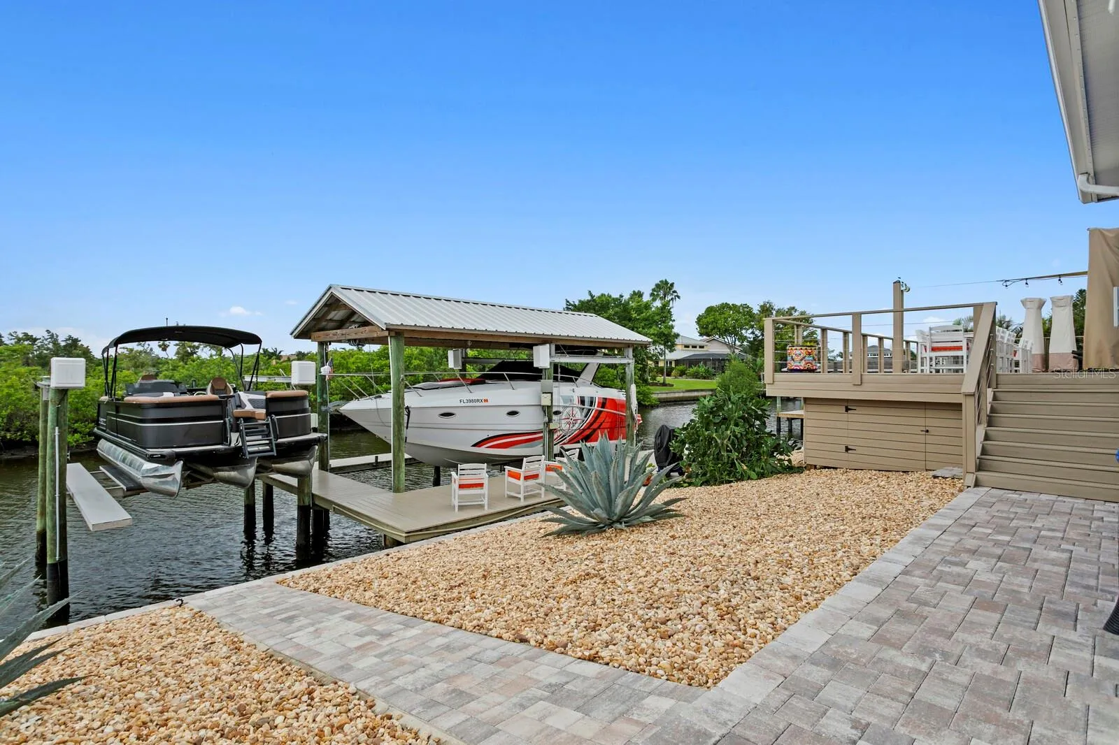 Paver walkway leads from deck down to covered boat lift