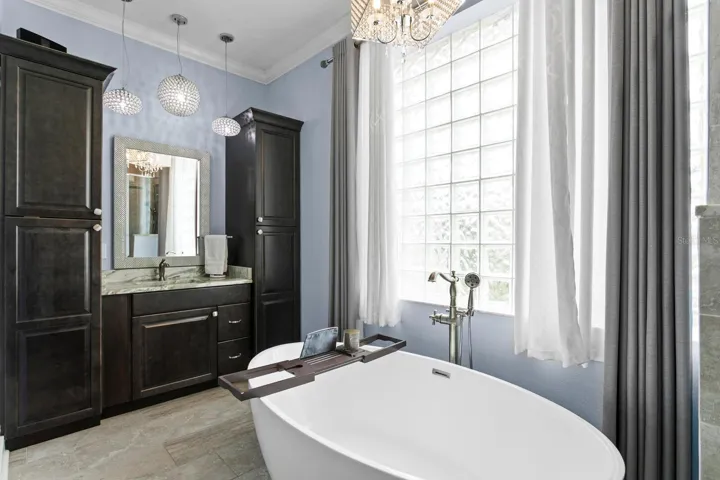 Ensuite bath features custom lighting, spit vanities, and glass-block window