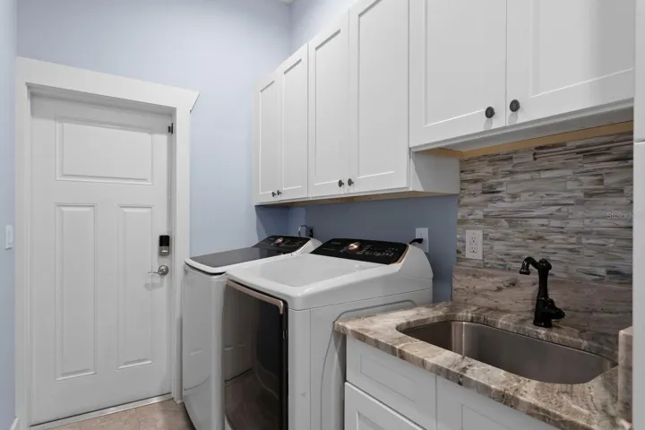 Utility room with large cabinets and utility sink leads to oversized 3-car garage