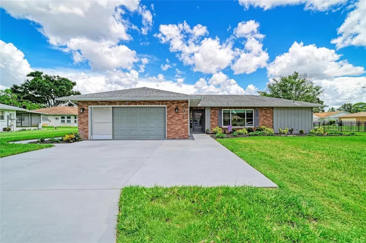 Front exterior with extended driveway and sliding screen doors on garage.