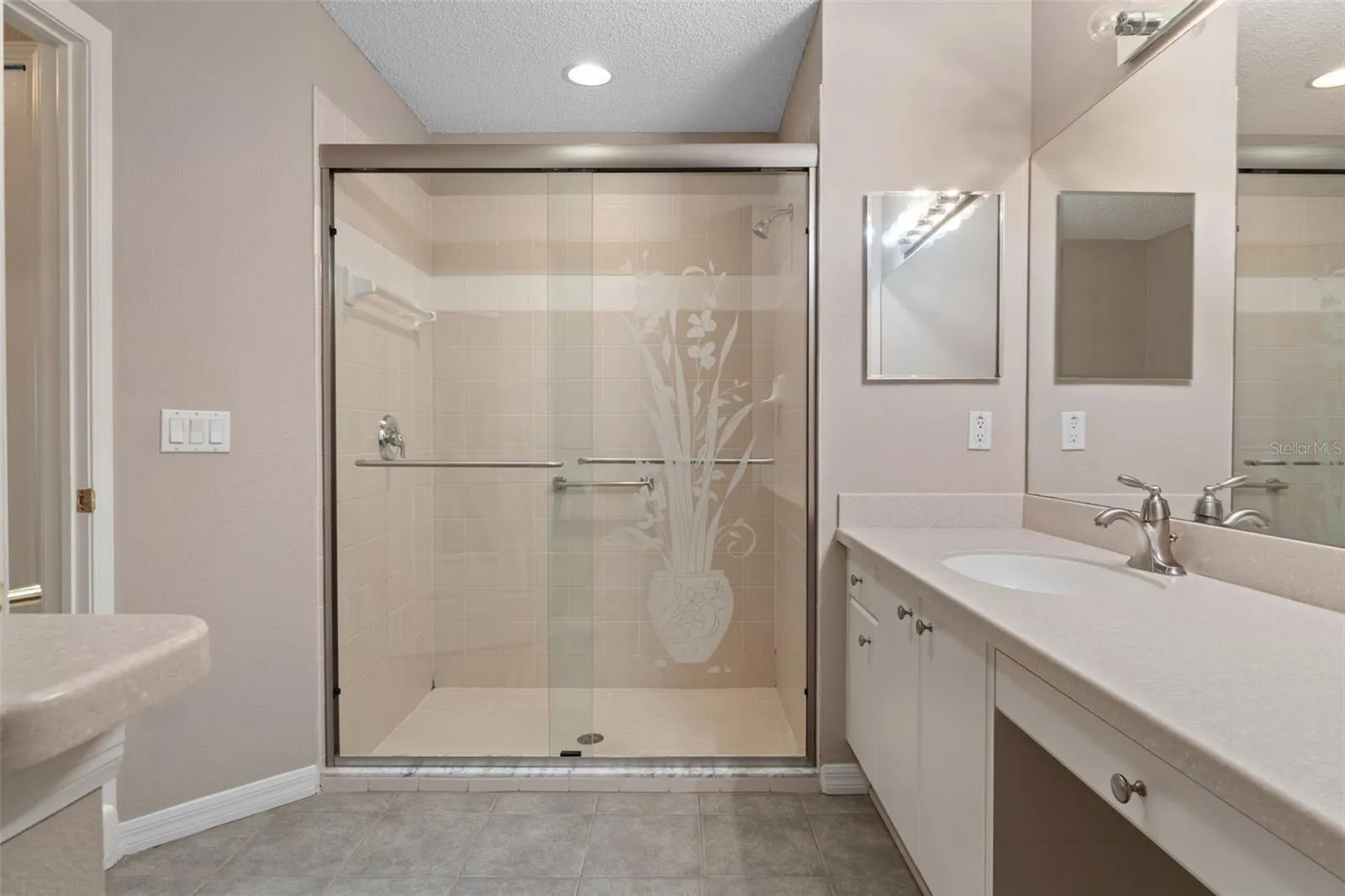 En-suite primary bath with walk-in shower, vanity, and built-in desk area.