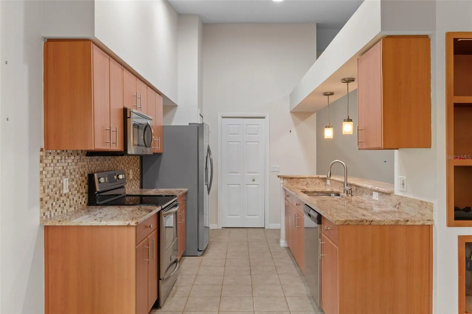 kitchen with granite counter tops and tile floor overlooking living area with bar