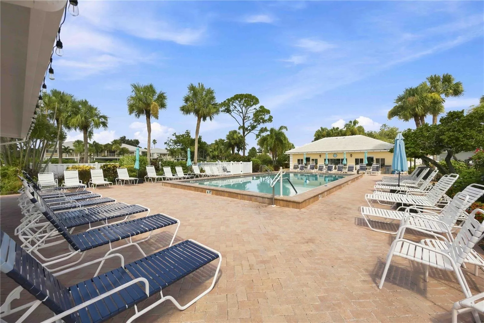 Sparkling community pool is surrounded by generous deck space, lounge seating and tropical scenery.