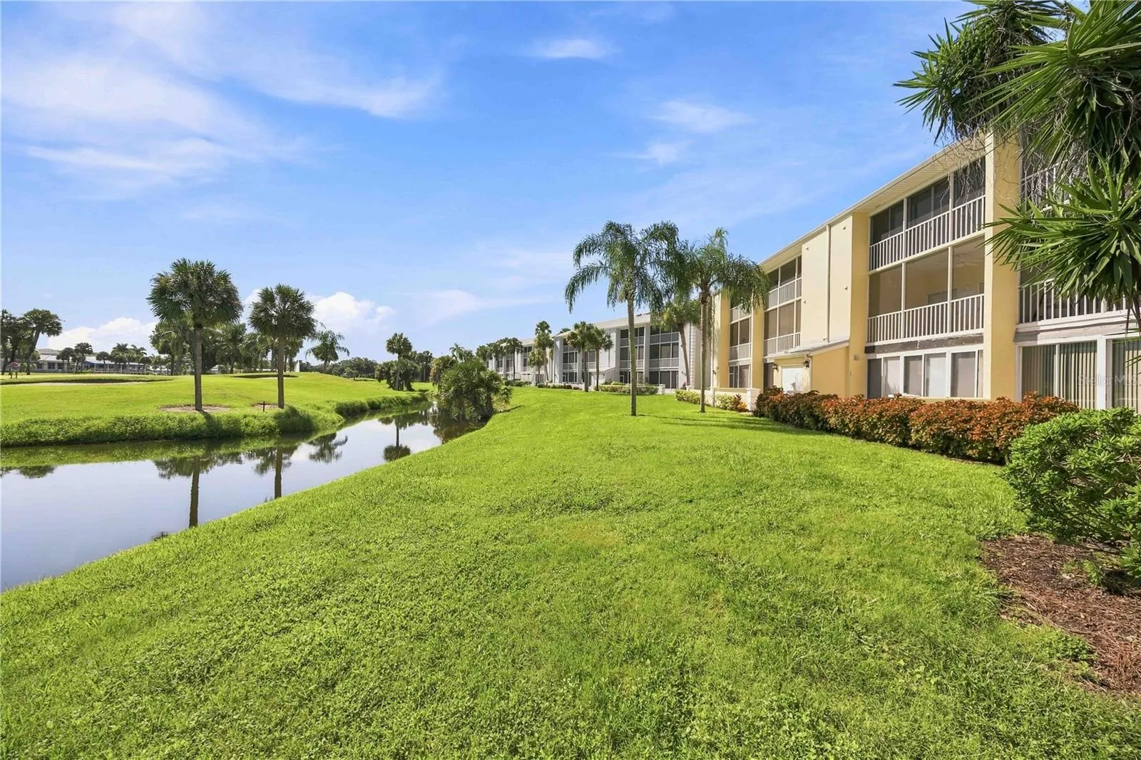 Waterside exterior showcases lush lawns, mature palms and the peaceful setting surrounding the building.