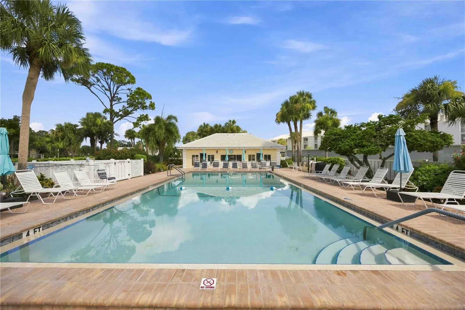 Sparkling community pool is surrounded by generous deck space, lounge seating and tropical scenery.