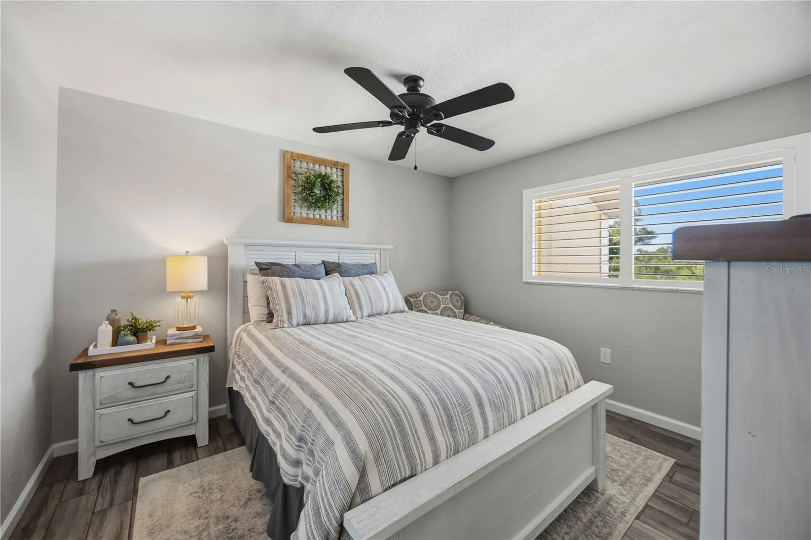 Bright secondary bedroom features attractive flooring, a ceiling fan and plenty of natural light.