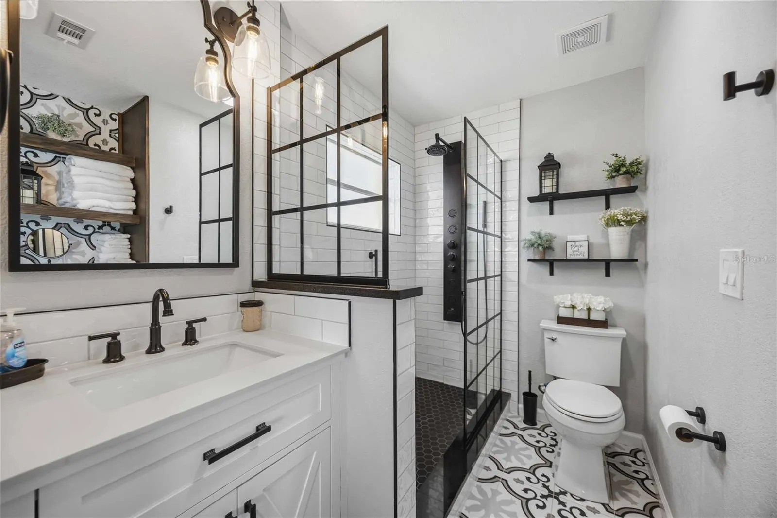 Beautifully renovated bathroom showcases a modern vanity, black fixtures and striking glass-enclosed shower.