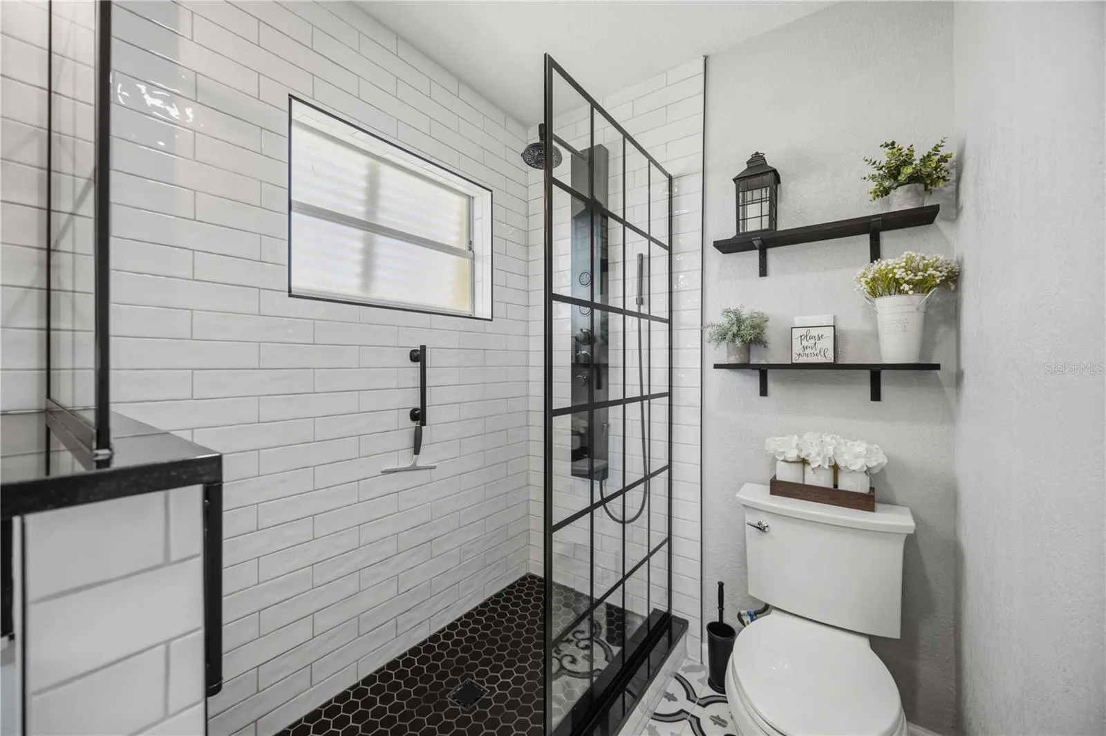 Spa-inspired shower features crisp subway tile, contrasting dark fixtures and a sleek glass enclosure.