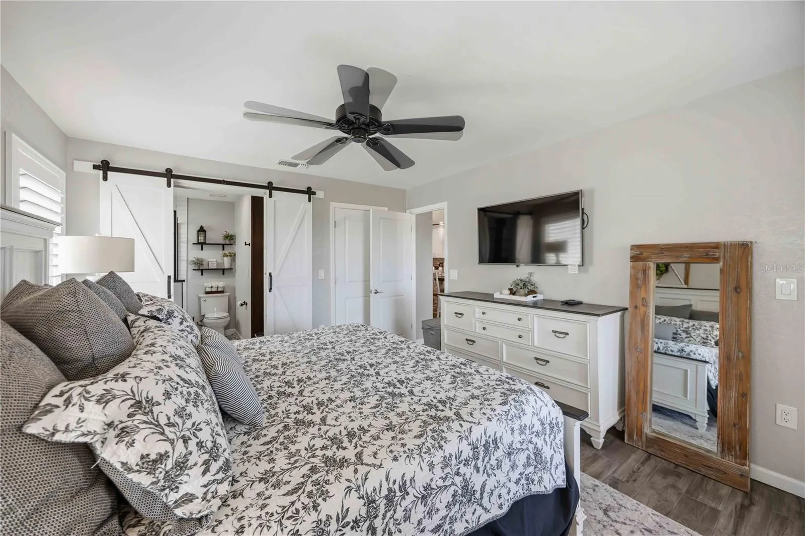 Another view of the primary suite highlights its comfortable scale and stylish barn-door detail.