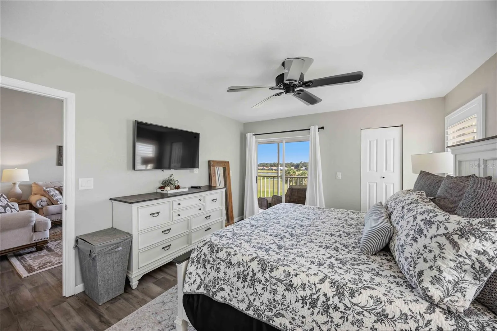 Spacious primary bedroom is filled with natural light and enjoys direct access to the screened outdoor living area.