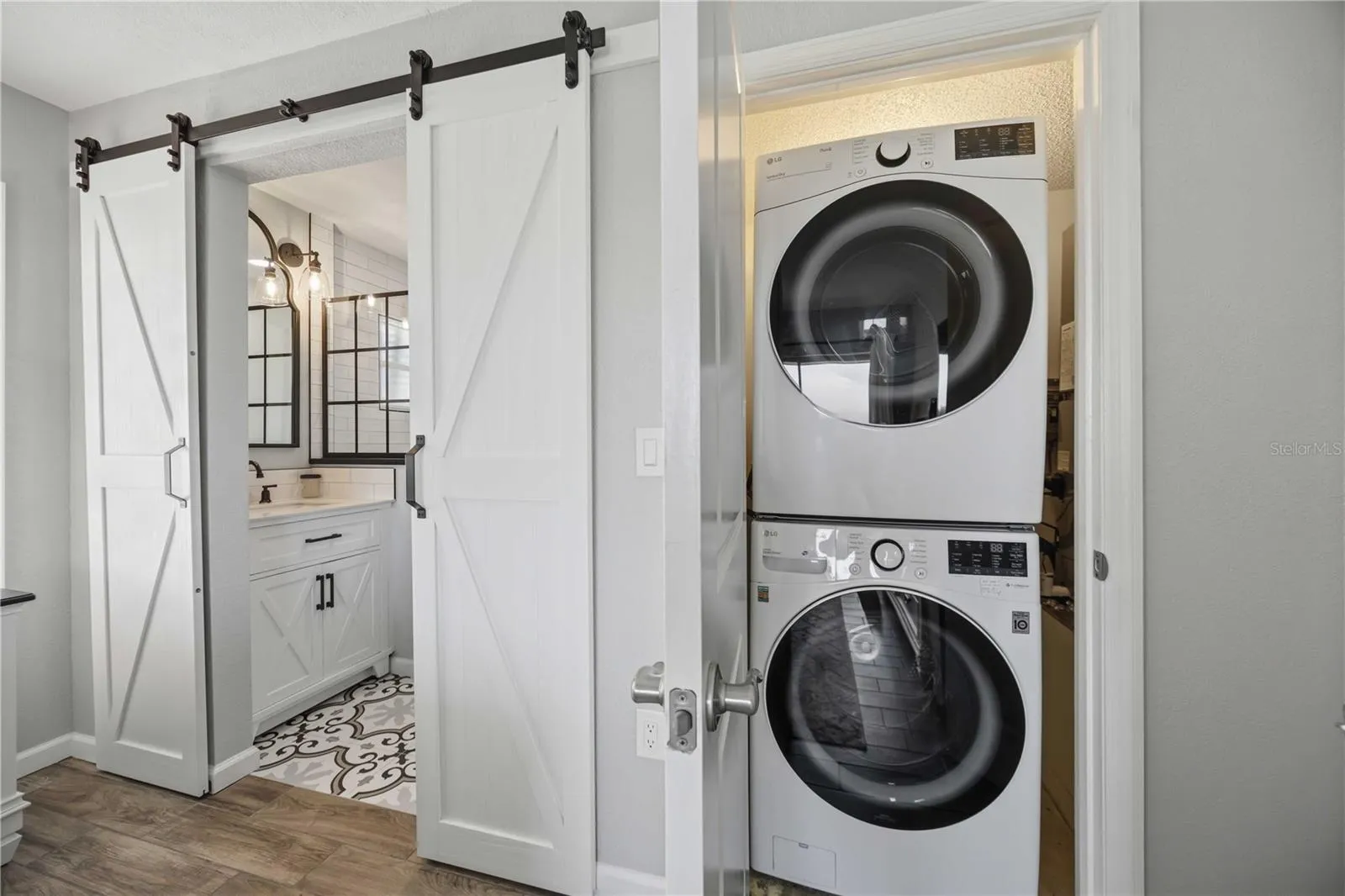 Stylish barn doors reveal the stunning bathroom. Closet with a convenient laundry area with stacked washer and dryer.