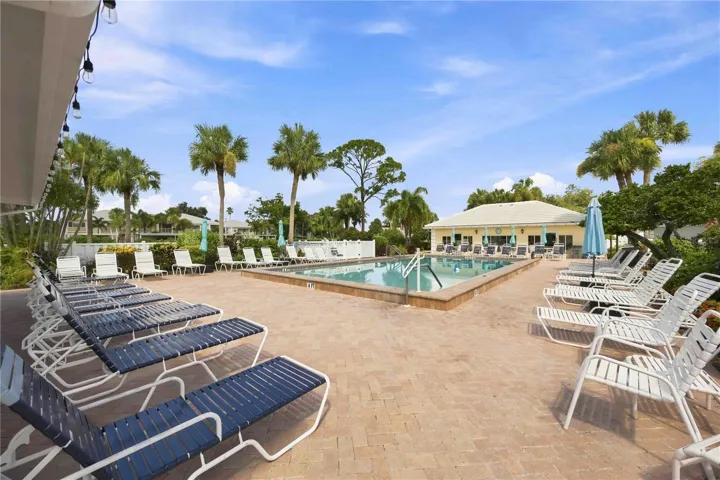 Sparkling community pool is surrounded by generous deck space, lounge seating and tropical scenery.
