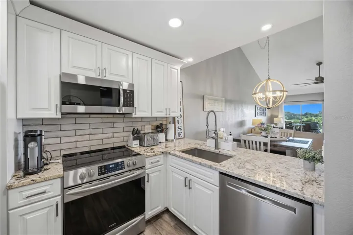Beautifully updated kitchen featuring crisp white cabinetry, stainless steel appliances, center island and wood-look flooring.