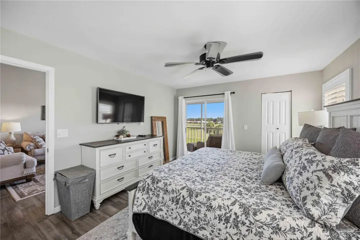Spacious primary bedroom is filled with natural light and enjoys direct access to the screened outdoor living area.