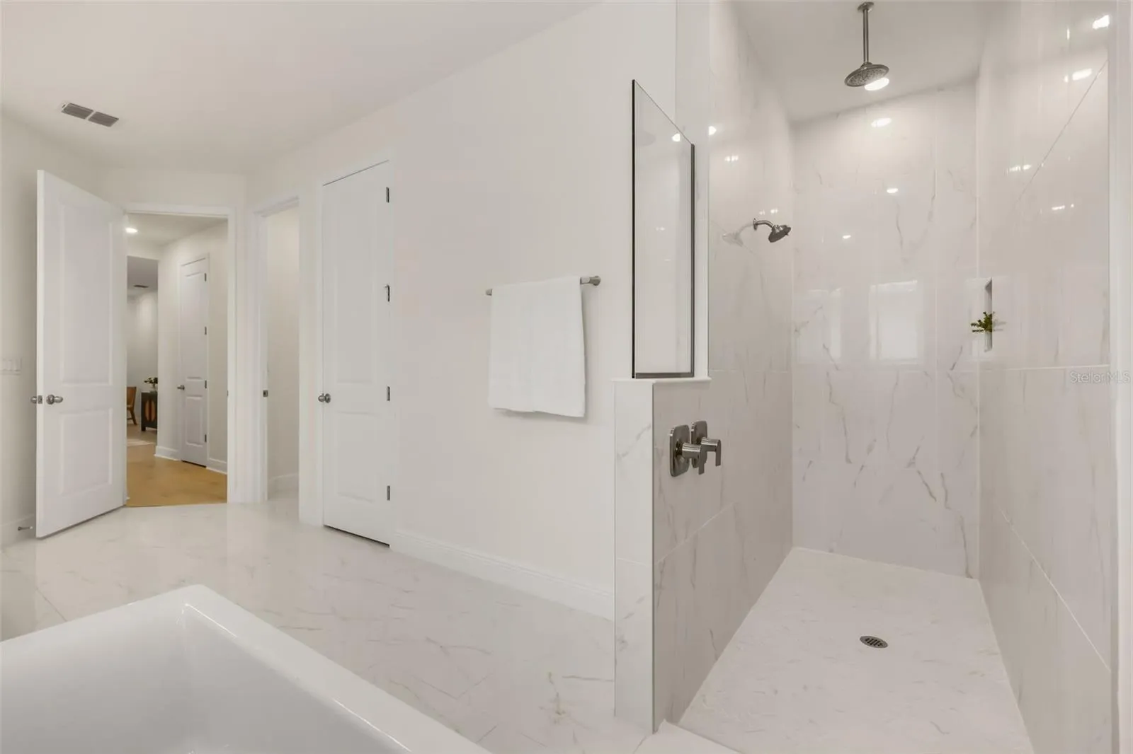 Luxurious primary bathroom with shower, dual vanity, soaker tub, and water closet