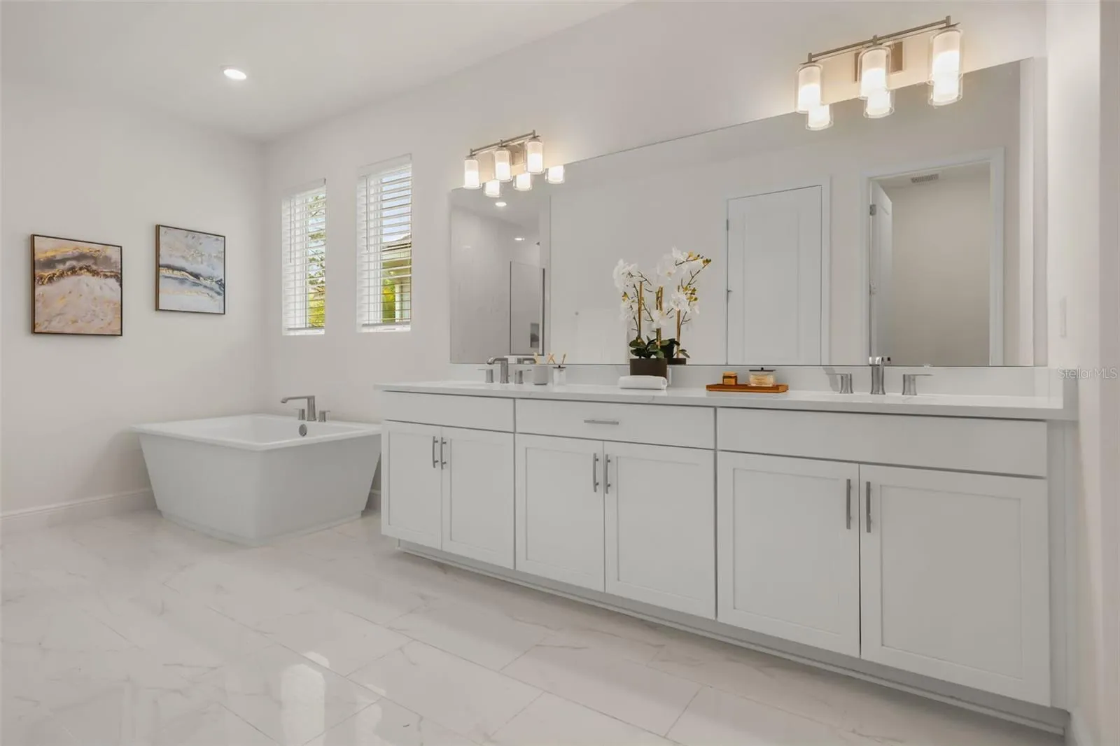 Luxurious primary bathroom with shower, dual vanity, soaker tub, and water closet