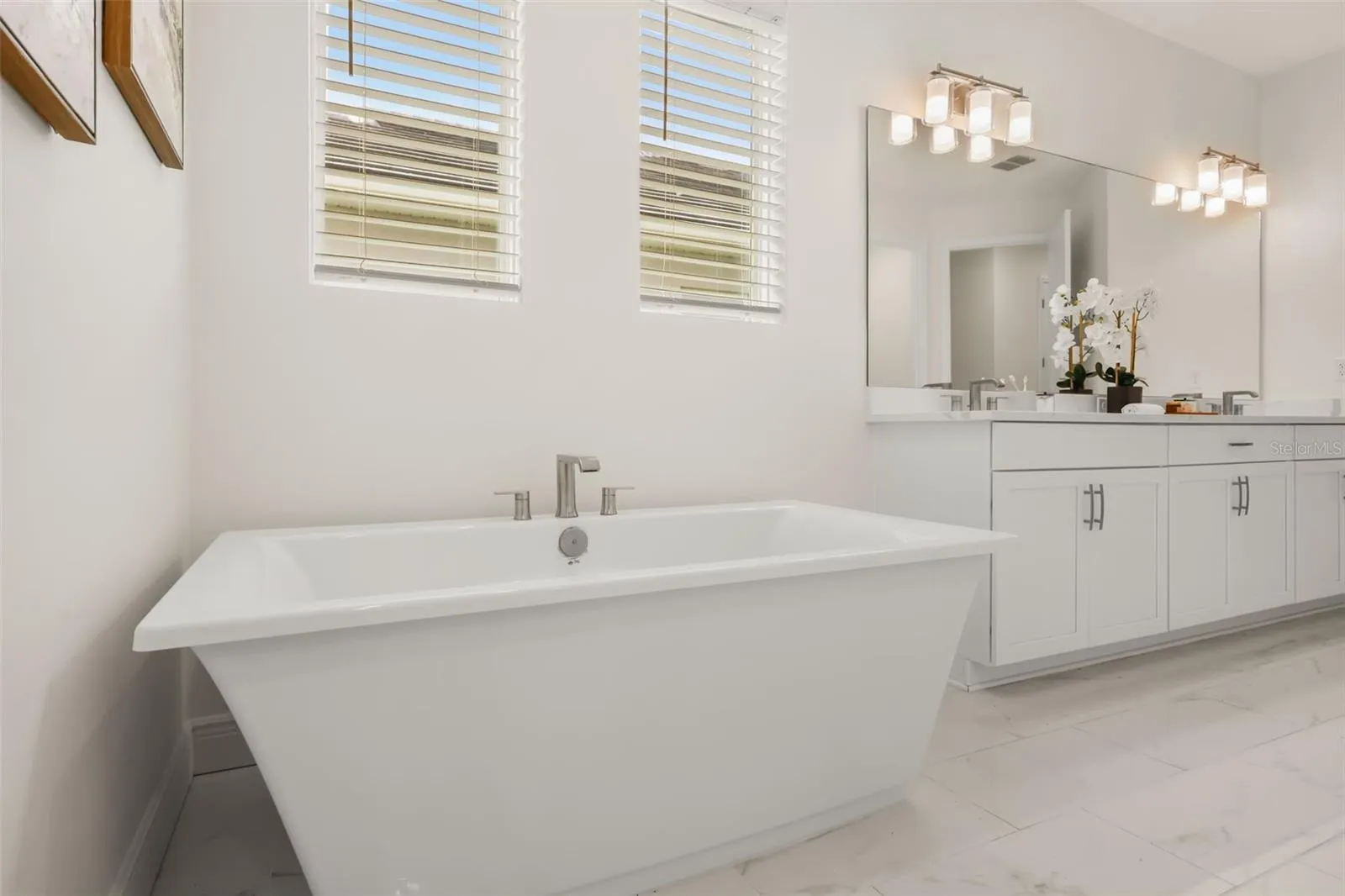 Luxurious primary bathroom with shower, dual vanity, soaker tub, and water closet