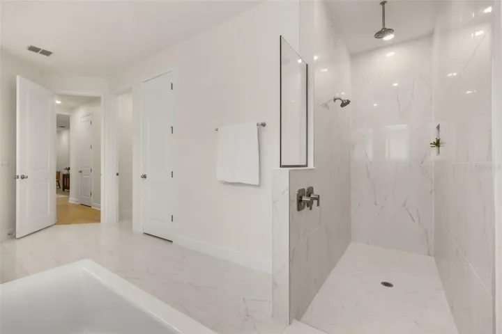 Luxurious primary bathroom with shower, dual vanity, soaker tub, and water closet