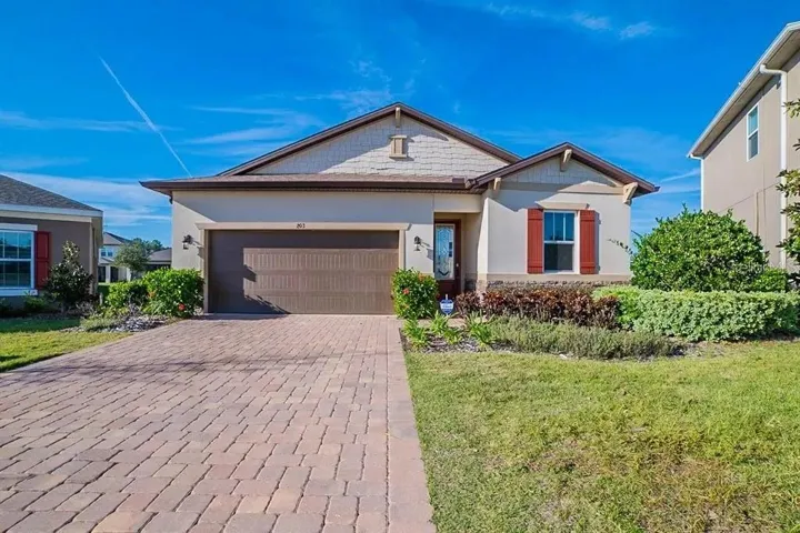 Front exterior with paver driveway and two-car garage.