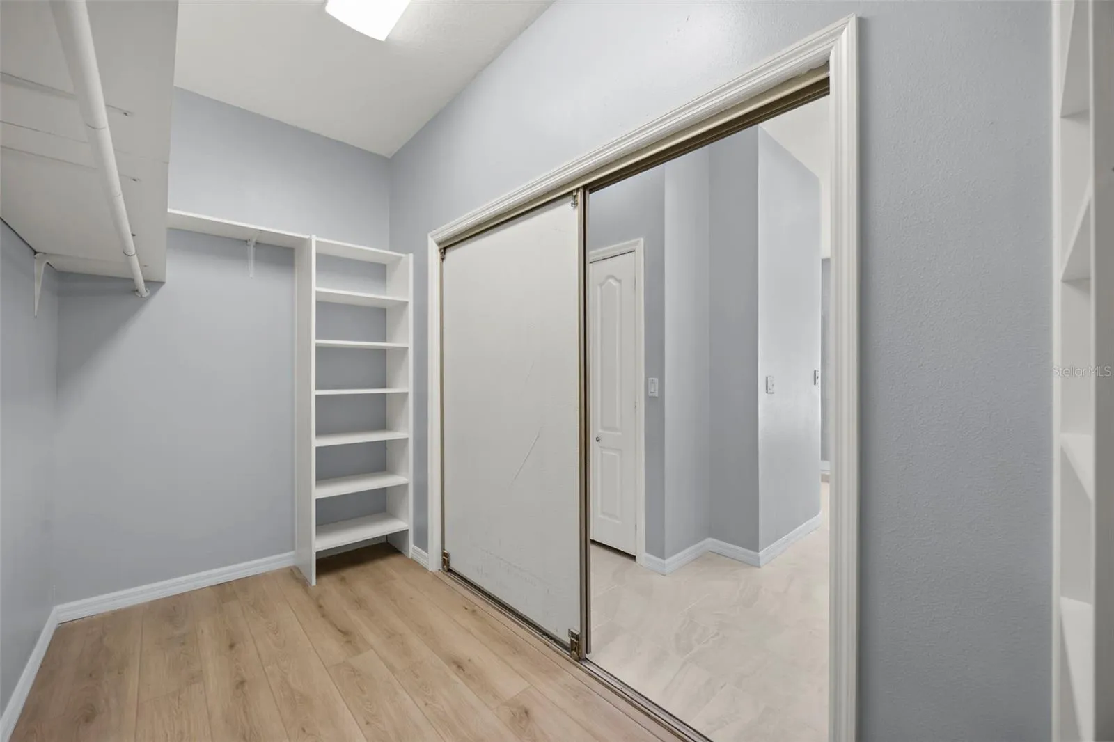 Primary walk-in closet with shelving and a floor safe