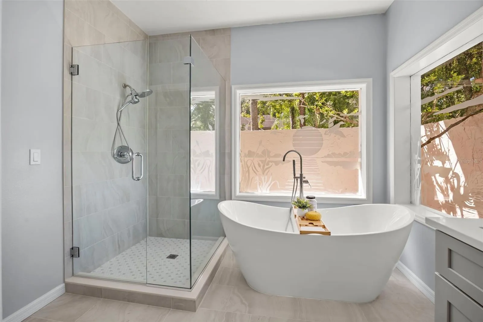Primary en suite with stand alone tub and shower. There's beautiful etched windows and an outdoor privacy wall