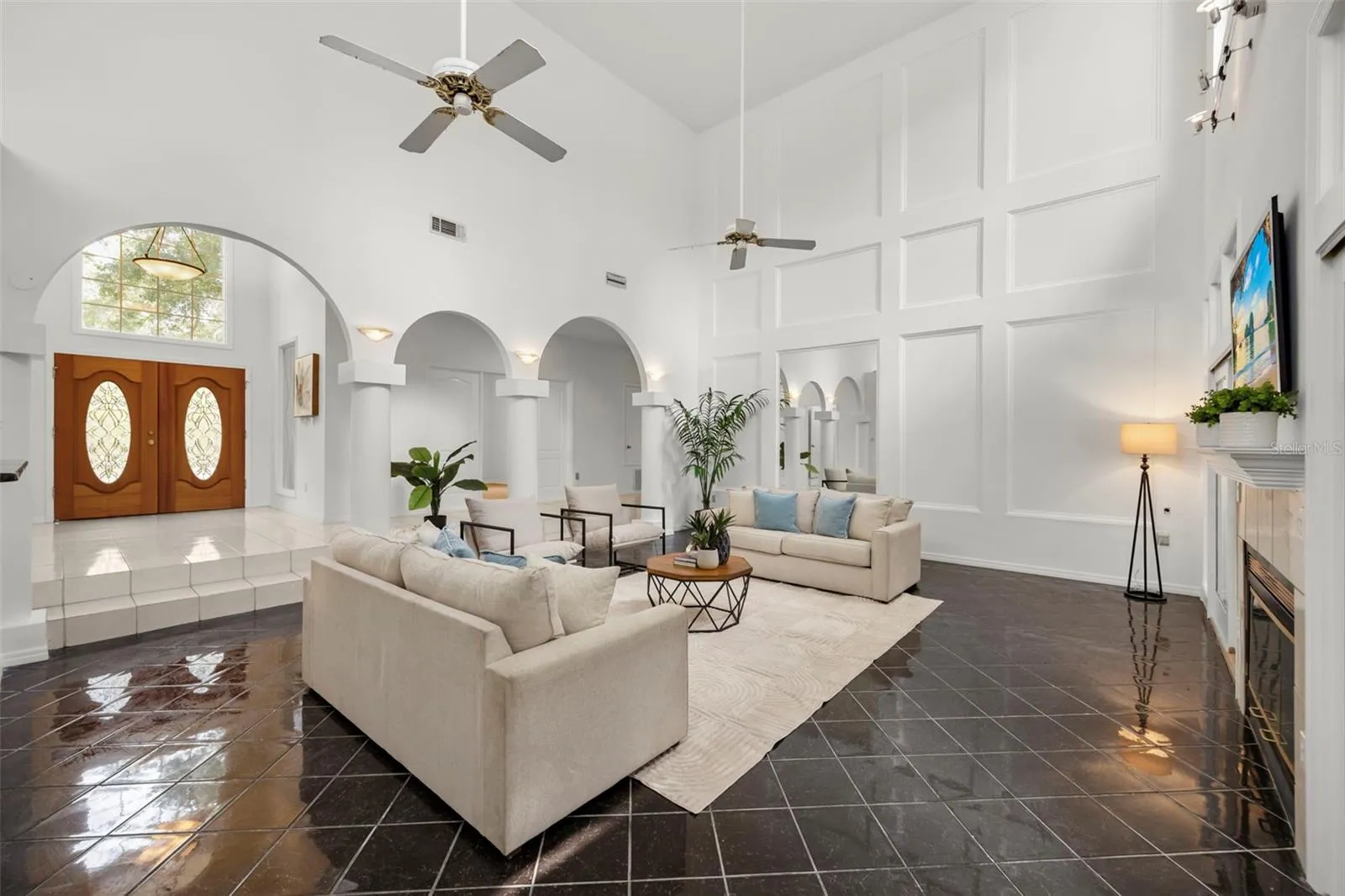 Grand Family room with 21 ft ceilings, picture framed walls, decorative columns and wood burning fireplace,