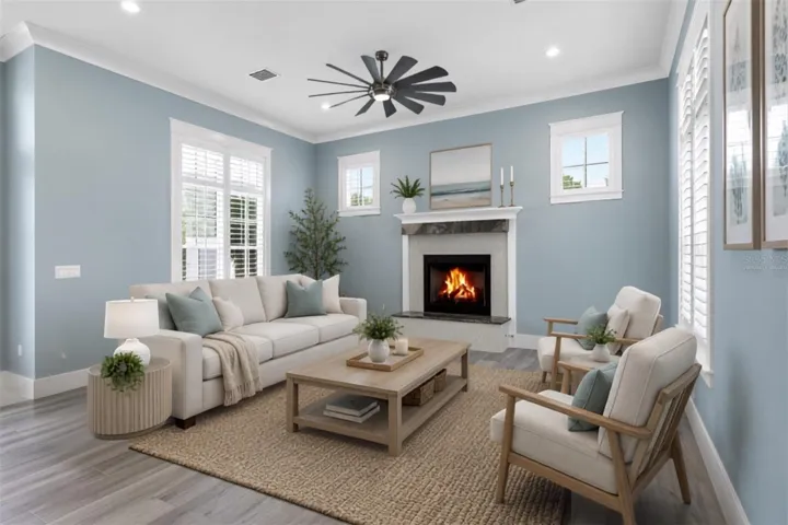 Virtually staged ground floor living space . A light-filled retreat with plantation shutters centered around a custom granite gas fireplace, perfect for unwind-and-relax evenings.