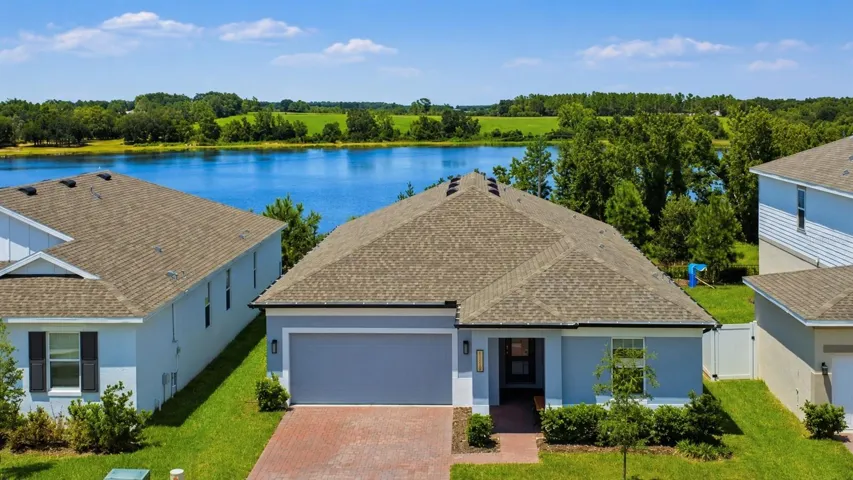 Exterior / Water View – Attractive single-story exterior with a paver driveway, covered entry, and tidy landscaping. The elevated perspective highlights the home’s scenic setting with a beautiful water view just beyond the property.