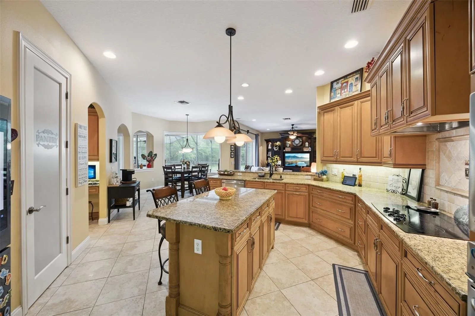 A second kitchen view shows the extensive cabinetry, island and open connection to the home.