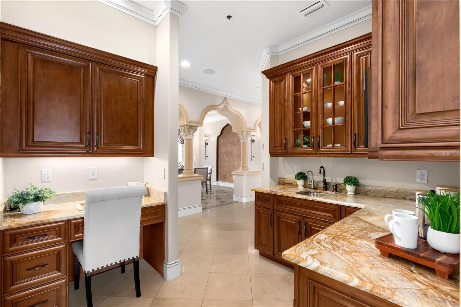 A beautifully appointed butler's pantry offers rich custom wood cabinetry, natural stone countertops and dedicated preparation space for effortless entertaining.