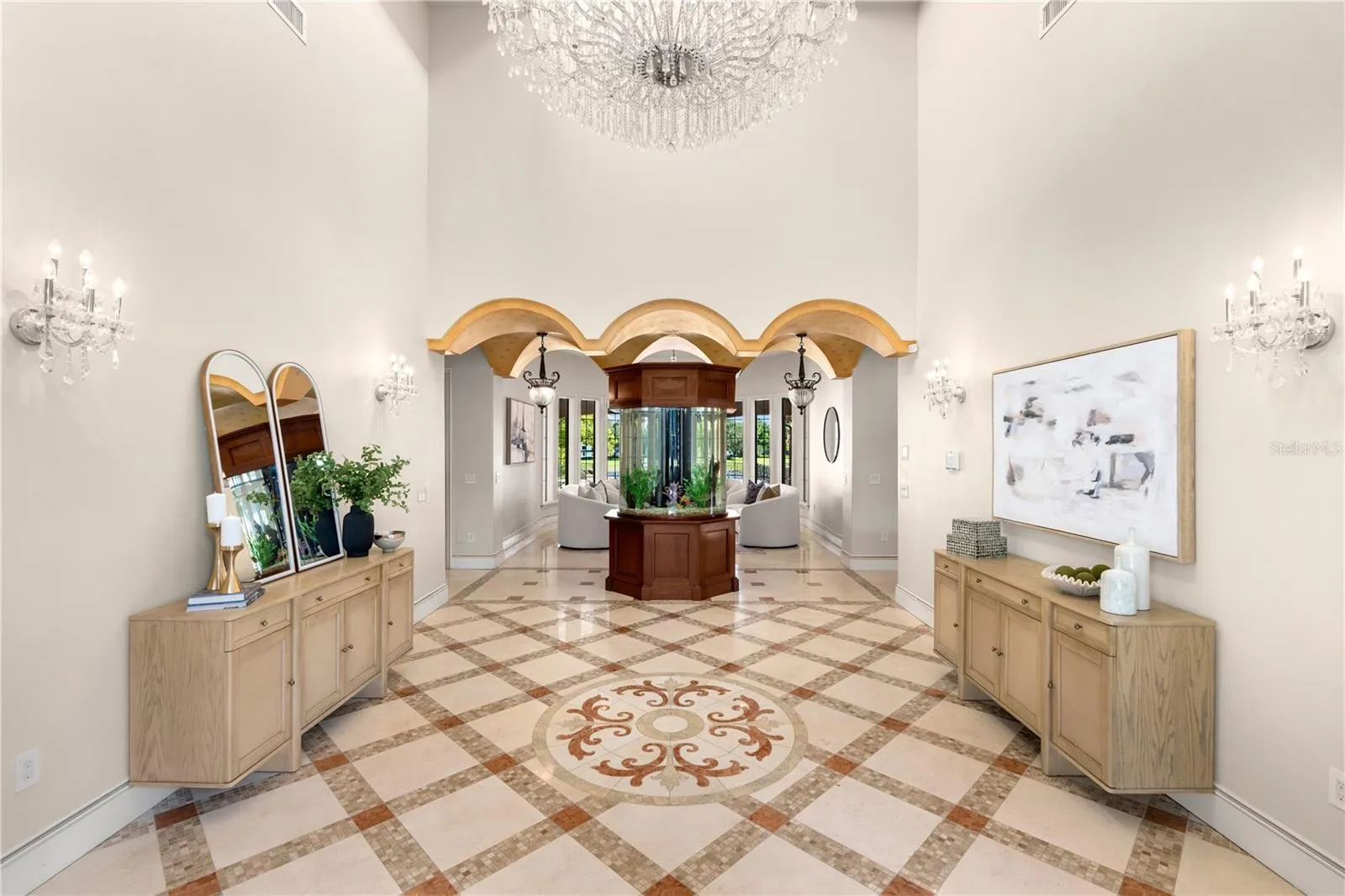 A magnificent two-story foyer makes an unforgettable first impression with a crystal chandelier, intricate travertine flooring, custom stone medallion, graceful arches and exquisite millwork.